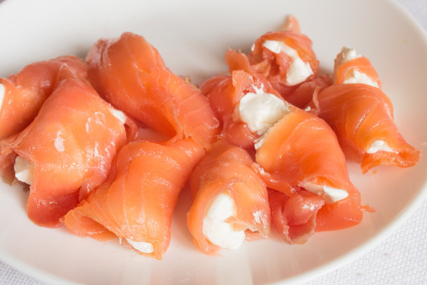 白色盘子上的烟熏三文鱼配奶油芝士。图片下载