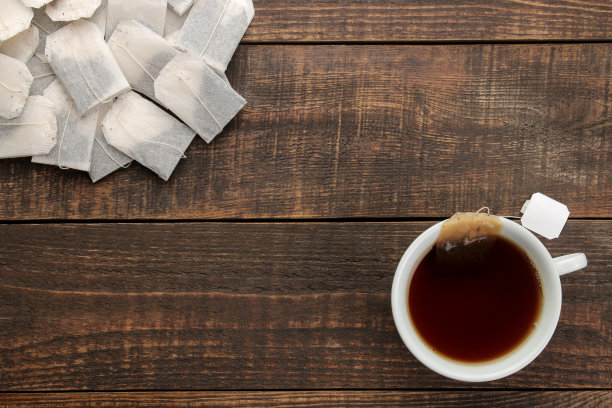 茶杯里有茶和茶包，放在棕色的木桌上。图片下载