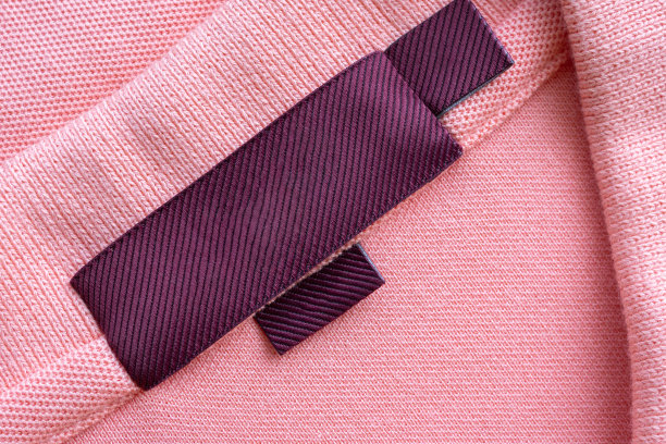 空白红色洗衣护理衣服标签上的粉红色织物质地的背景图片下载
