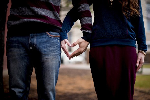特写镜头一对夫妇用他们的手做一个心形和模糊的背景图片下载