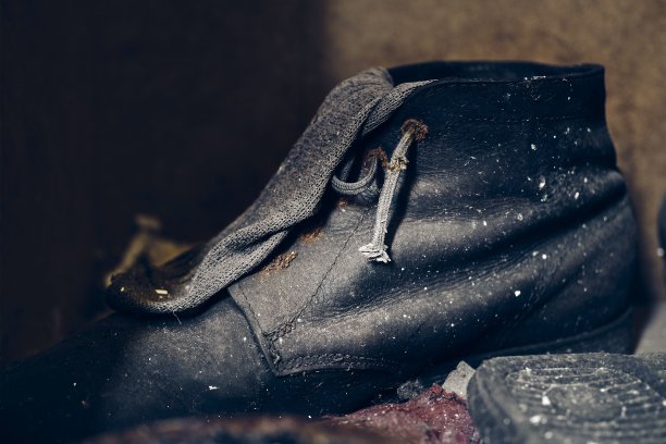 在模糊的背景上，一个破旧的黑色鞋子的特写镜头图片下载