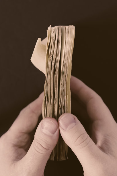 一个男人的手打开一个旧的日记本的特写垂直镜头图片下载