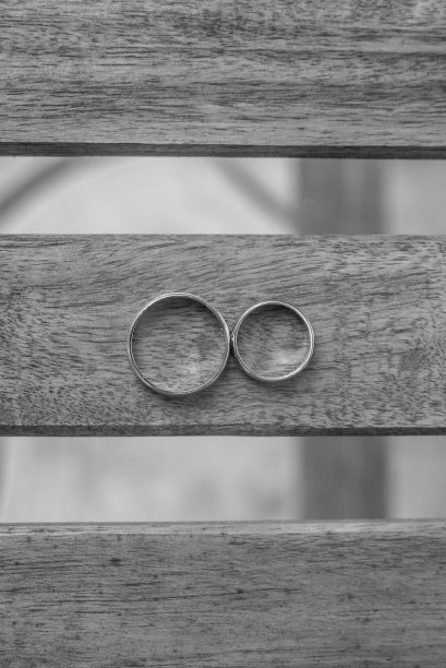 垂直拍摄的结婚戒指在一个木桌黑白图片下载