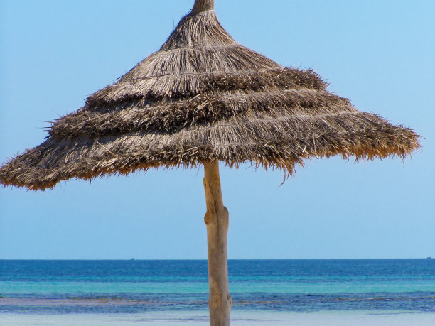 海滩稻草伞对着海的地平线图片下载