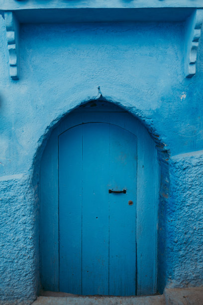 垂直拍摄的一扇古老的蓝色木门的老建筑在舍夫chaouen，摩洛哥图片下载