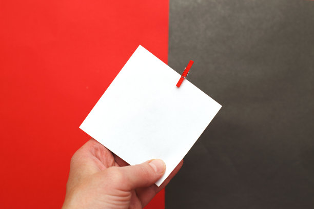 人手握的贴纸与空模型文本挂在大头针上红黑底。图片下载