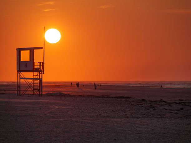 德国Juist岛海滩上的金色夕阳和救生员小屋图片下载