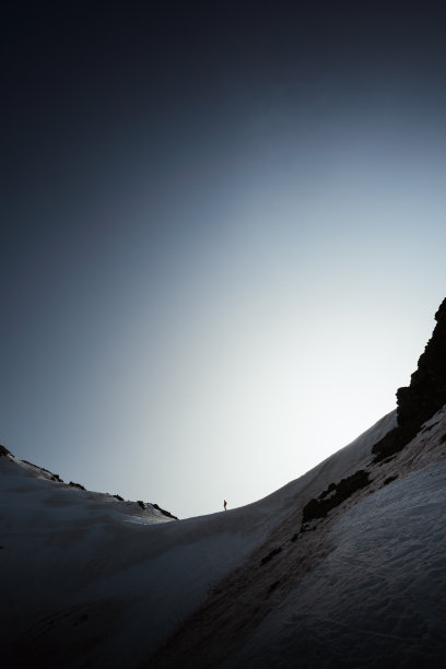 一个人在白雪覆盖的山上徒步的垂直照片图片下载