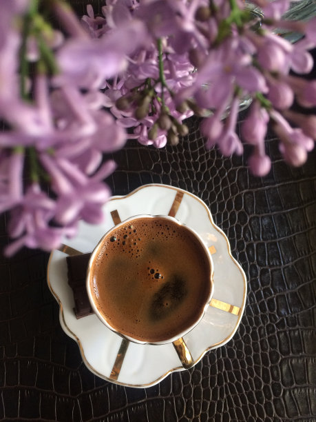 俯视一杯咖啡在一个皮革桌子和紫色的花图片下载