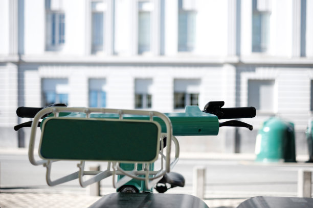 特写电动自行车车把与白色建筑在前面。图片下载