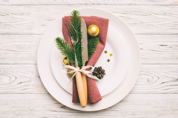 圣诞餐桌的地方设置与圣诞装饰和盘子，牛，叉子和勺子。圣诞假期背景。带有复制空间的俯视图图片下载