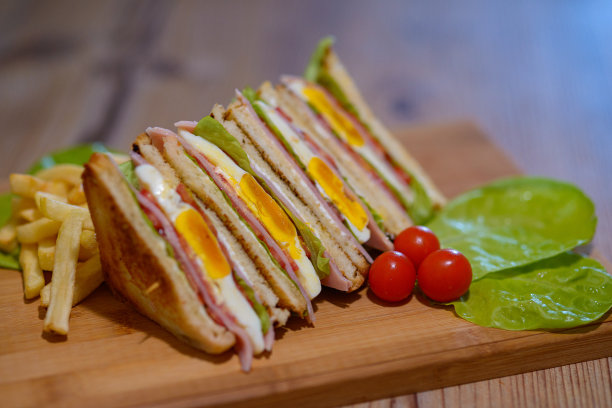 三明治与鸡蛋和火腿的选择性聚焦镜头在切菜板上图片下载