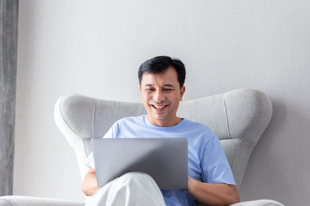 快乐的商人在家工作时，通过在线笔记本电脑和手机与团队进行股票交易图片下载