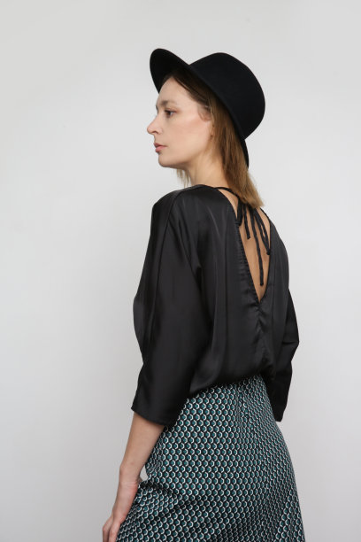 一系列的工作室照片，迷人的年轻女模特穿黑色衬衫和几何印花中长裙。图片下载