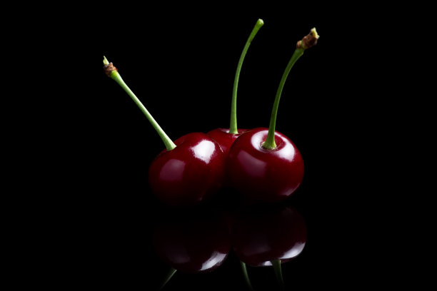 红色樱桃浆果在黑色背景与镜子。三个樱桃图片下载