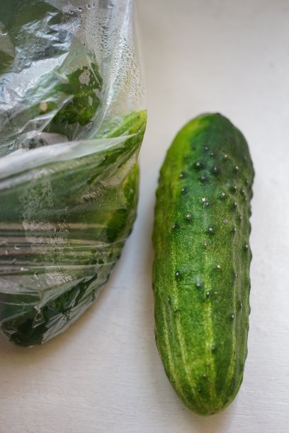 成熟的绿色黄瓜在一个透明的袋子和白色的桌子上特写视图图片下载