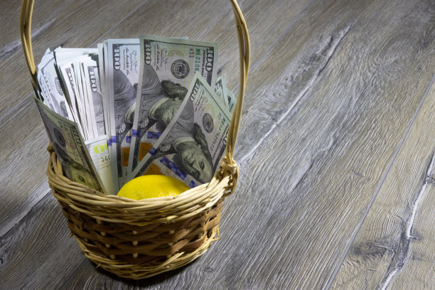 灰色的木桌上摆着柳条篮子，里面放着一百美元的美钞和柠檬图片下载