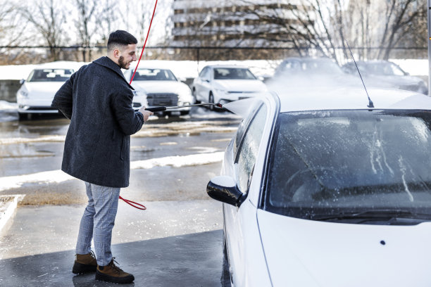 一个年轻的商人正在洗车店清洗汽车。图片下载