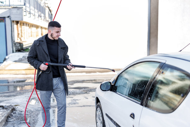 一个年轻时髦的男人正在洗车处洗车。图片下载