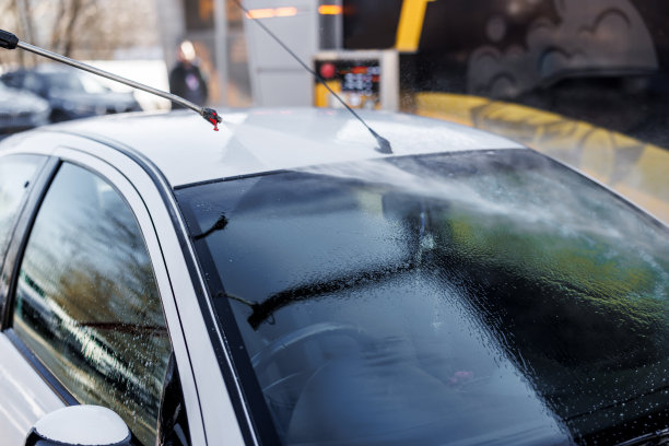 一个时髦的年轻人正在用水泵洗车。图片下载