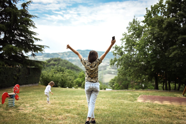 母亲和女儿在一起的家庭时光。一个举起手臂的女人的背影。幸福的家庭观念。图片下载