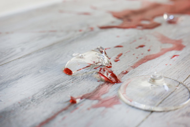 玻璃碎在地板上，玻璃碎片满地飞，红酒洒了出来。家庭暴力、单相思或压力感的概念图片下载