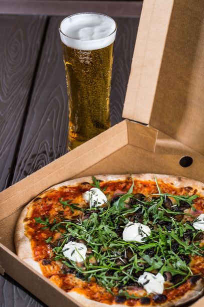 垂直拍摄的新烤披萨与芝麻菜和蘑菇在工艺盒。图片下载