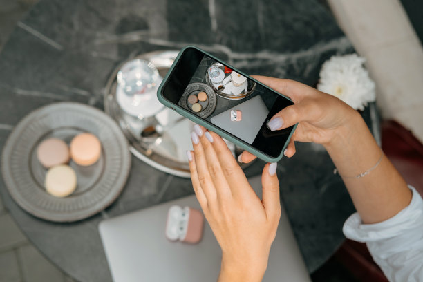 特写的照片，女人的手拿着智能手机的桌子上有咖啡和糖果图片下载