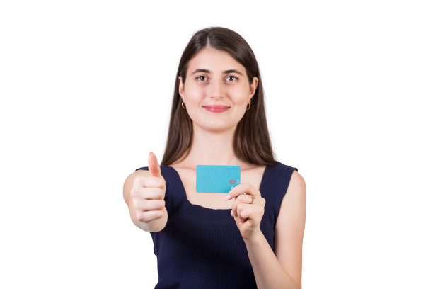 快乐的年轻女子竖起大拇指，另一只手拿着信用卡，在白色的背景与复制空间隔离。批复标志，银行营销图片下载