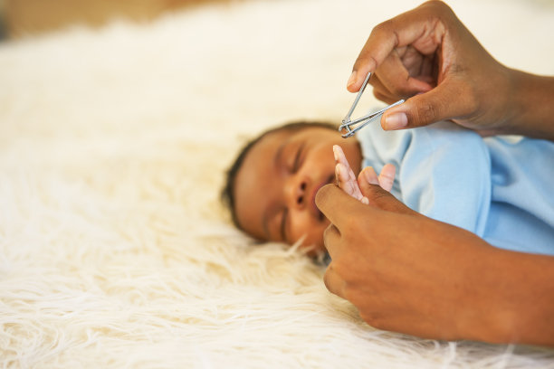 母亲用指甲钳给刚出生的婴儿剪指甲。图片下载