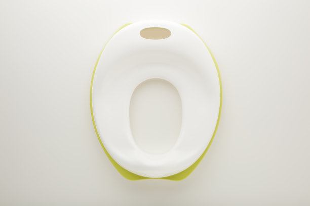 浅灰色桌子背景上的新白色马桶座盖。特写镜头。使孩子习惯上厕所。自顶向下视图。图片下载
