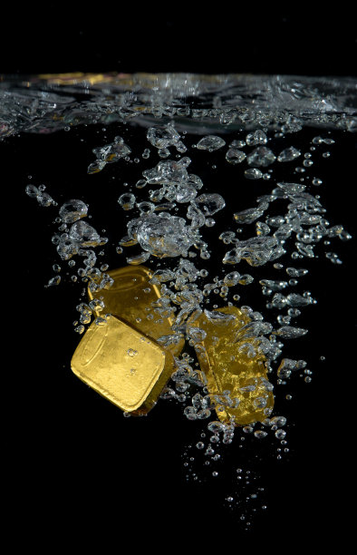 金条溅到水在黑色背景，商业和金融。图片下载