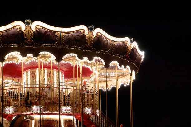 儿童旋转木马在晚上的娱乐公园在夜间照明。户外复古彩色夜光旋转木马在黑暗中。复古旋转木马细节，马匹。圣诞节娱乐图片下载