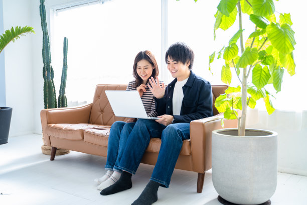 一对夫妇，两对微笑的男女坐在客厅的沙发上视频聊天。图片下载