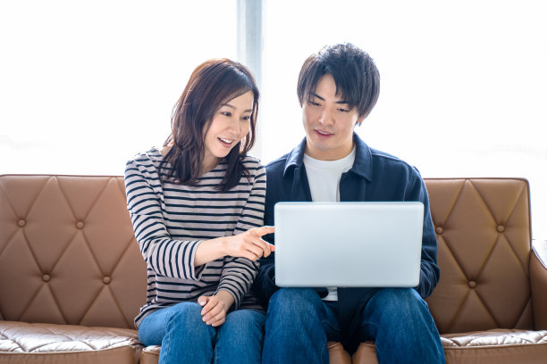 一对夫妻微笑的男人和女人坐在客厅的沙发上，搜索网络放松图片下载