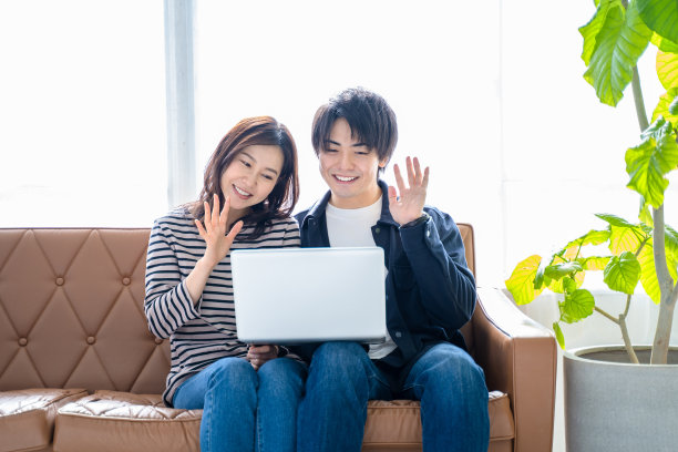 一对夫妇，两对微笑的男女坐在客厅的沙发上视频聊天。图片下载