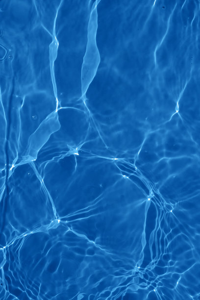 离焦模糊透明蓝色清澈平静的水面纹理与飞溅和气泡。新潮抽象的自然背景。阳光下的水波与复制空间。蓝色水彩闪闪发光图片下载