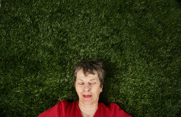 一位年长的妇女仰卧在草地上，看上去洋洋自得、心满意足而又安详图片下载