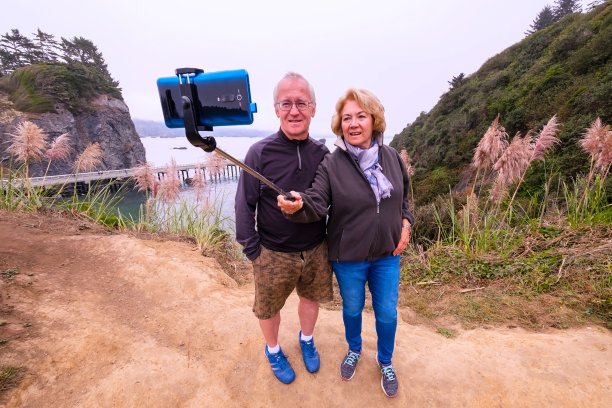 一对微笑的老年夫妇在悬崖边自拍图片下载