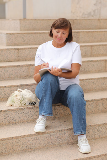 成年女性远程工作，成人接受高等教育，女性坐在户外楼梯上用笔记本写笔记，自由职业者。大学学习计划，学术教育课程。图片下载