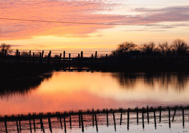 村里河上的铰链小桥。村里的粉橘色晚景图片下载