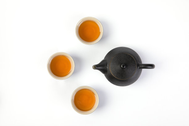 一个黑色茶壶的顶部，三个茶杯孤立在白色的背景上图片下载