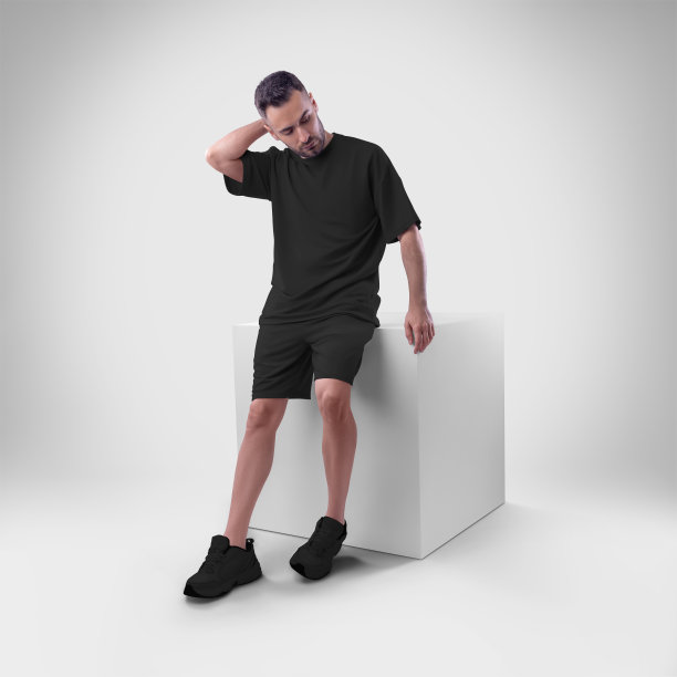 孤立的模型时髦的黑人男子的超大t恤与短裤上的人坐在立方体上。图片下载