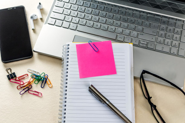 一张有笔记本，记事本，笔记本电脑和办公用品的桌子的特写。在线学习概念图片下载