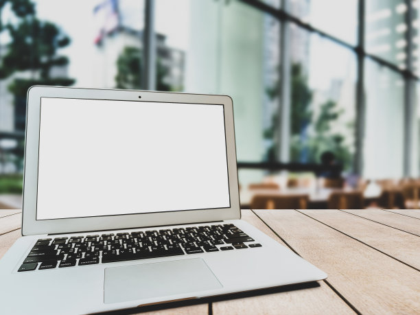 咖啡店桌子上空白屏幕的笔记本电脑。图片下载