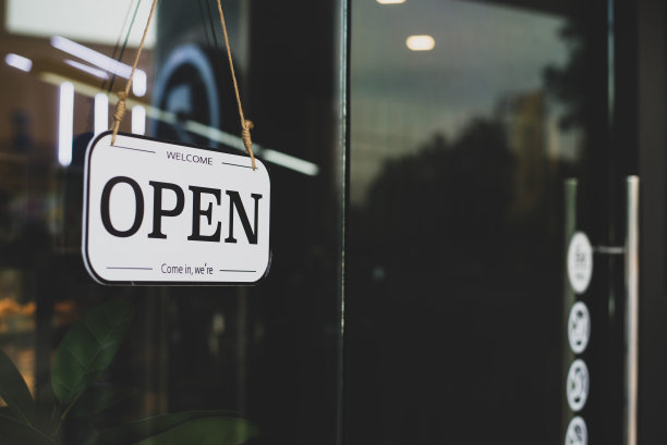 咖啡店和餐厅门前的玻璃门上挂有开关翻转标志。木制标牌，上面写着地方的地位。表示欢迎。我们打开。请进。图片下载