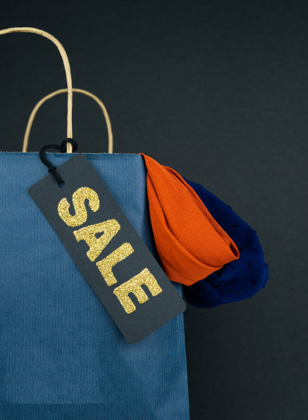 蓝色纸袋，黑色标签，黑色背景销售文字。副本的空间。垂直的照片。图片下载