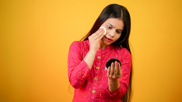 美丽的年轻印度女子拿着棉花贴脸。白底上完美皮肤的女人的照片。美容护肤理念图片下载