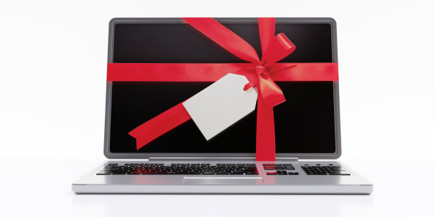 电脑购物，送礼。红色丝带蝴蝶结在笔记本电脑上隔离在白色图片下载