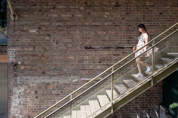 亚洲单身女性爬砖墙旁的楼梯。图片下载